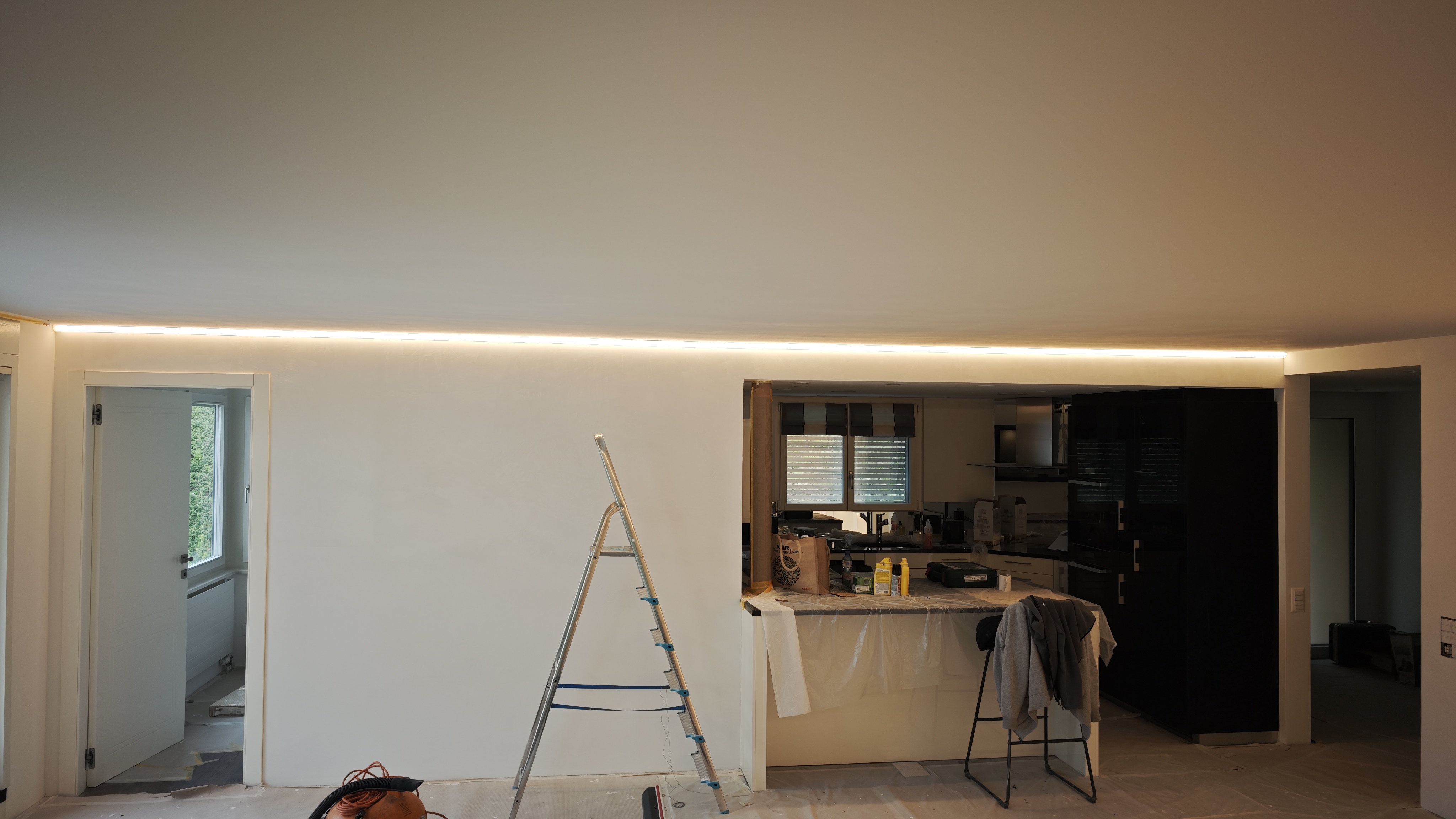 Wohnraum mit LED-beleuchteten Einbauregalen und einer Lichtlinie an der Decke